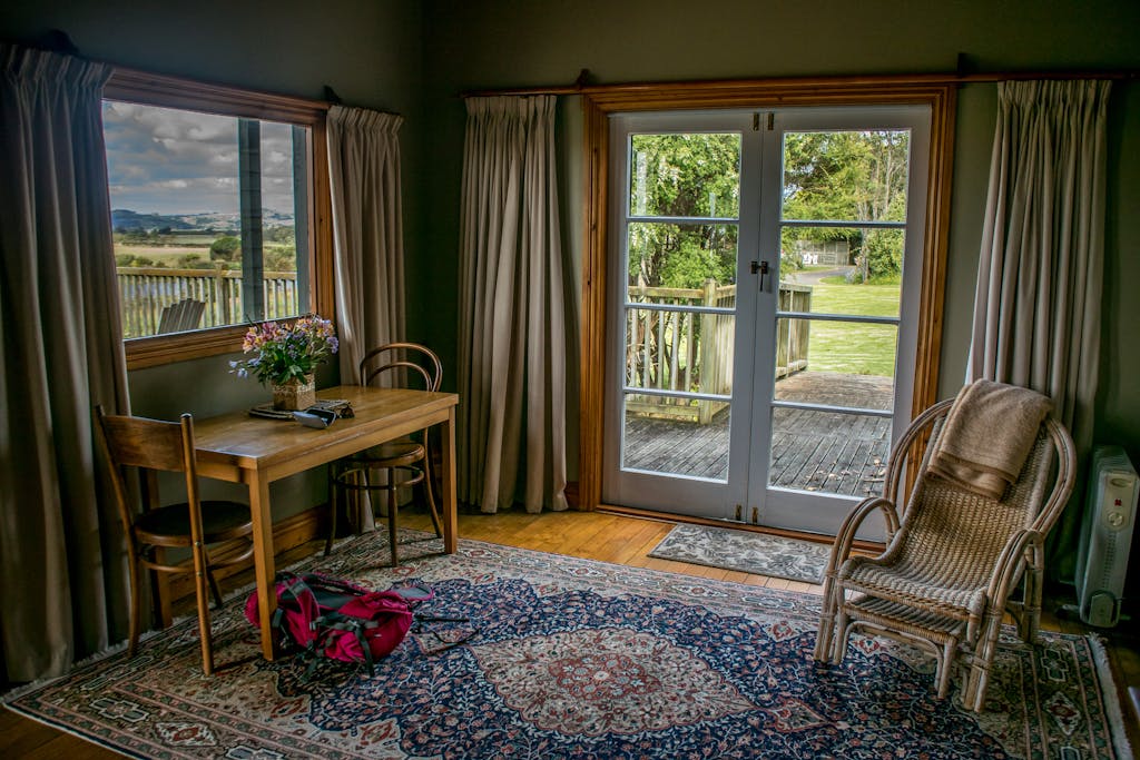 A charming room with vintage decor and a view of a lush garden through open doors.