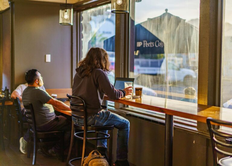Remote worker with laptop at a coffee shop in one of the best Ozarks towns for remote workers